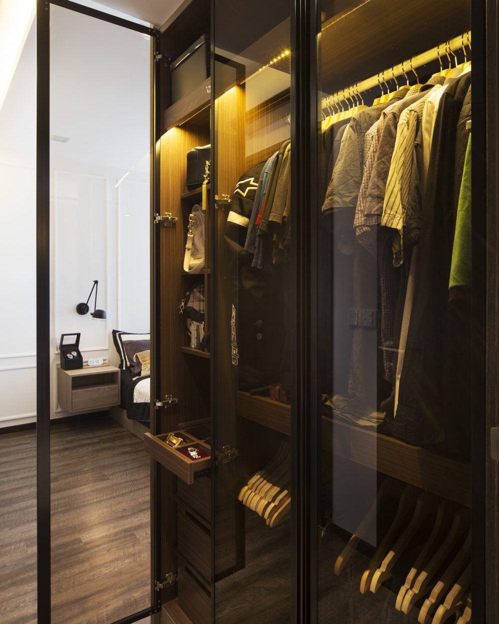 Smoked glass doors and warm LED strip lighting reveal a fully fitted walk-in wardrobe, complete with a felt-lined jewellery drawer.