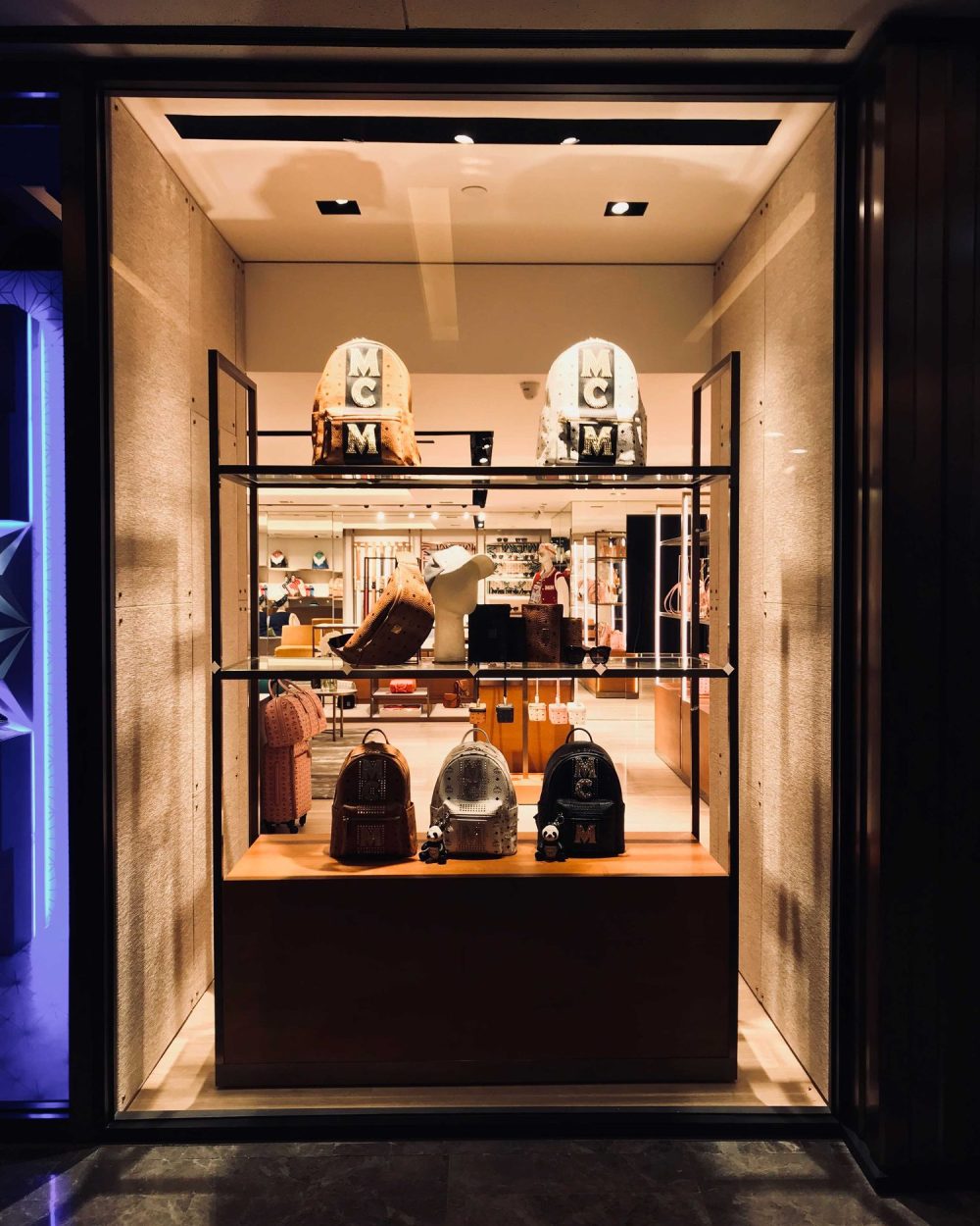 A display case of MCM-lettered backpacks, a cap and sunglasses against the store's mirrored walls.