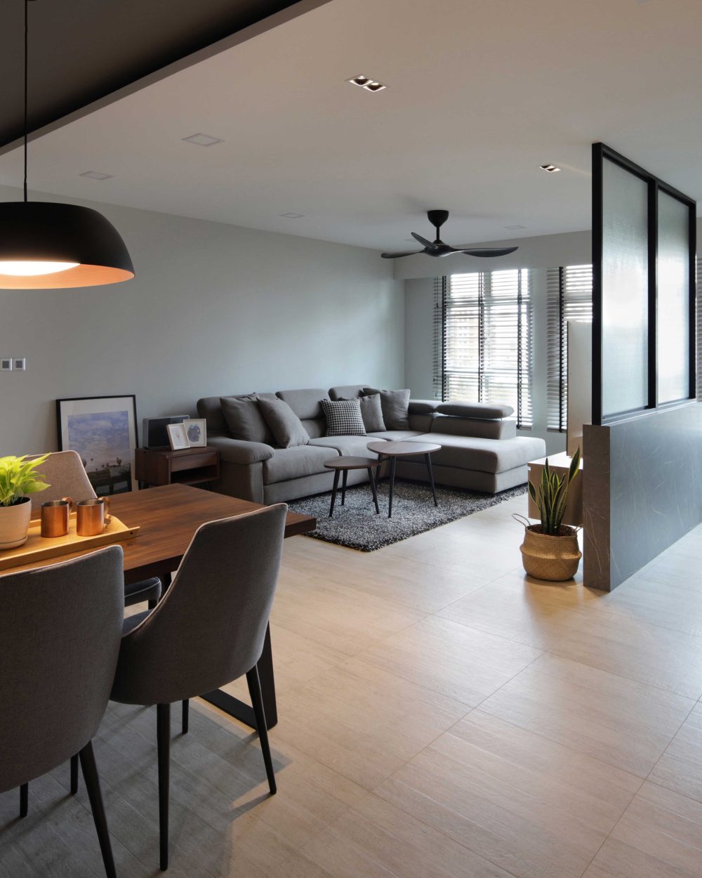 White lacquered cabinetry and a black dome pendant frame the dining table, with the frosted glass partition continuing the sightline through to the st