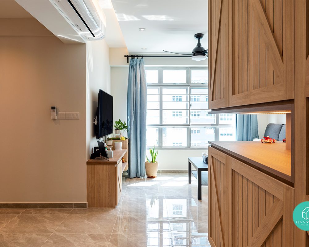 Soft blue curtains and a slim TV console line the corridor between living and dining, with the timber storage wall continuing alongside.