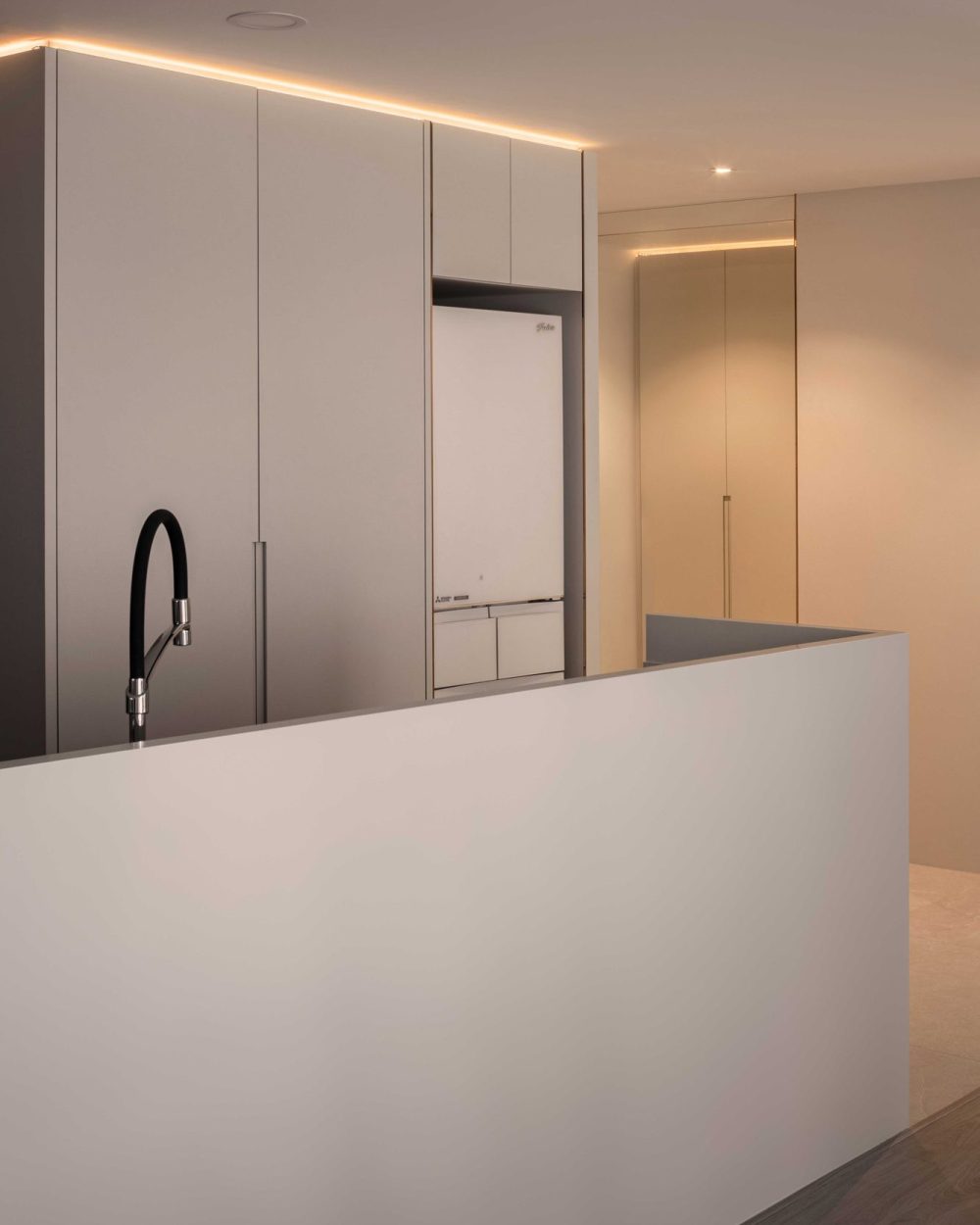 A full-height refrigerator is seamlessly integrated into the white cabinetry, keeping the kitchen wall visually uninterrupted.
