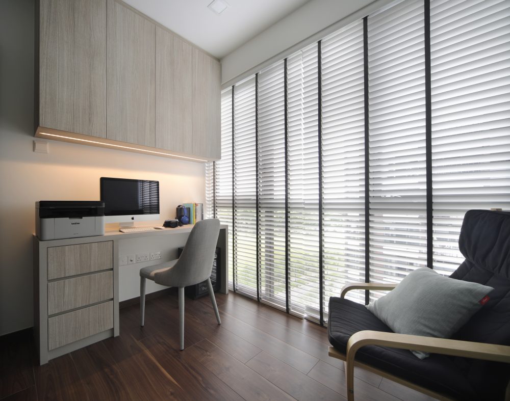 A full-width desk and overhead cabinetry make efficient use of this home office nook, with floor-to-ceiling blinds controlling the light.