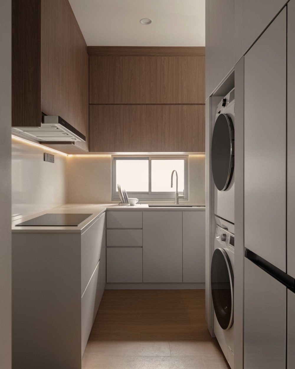 A stacked washer and dryer are built into warm timber cabinetry, keeping the utility area tidy and out of sight from the main kitchen.
