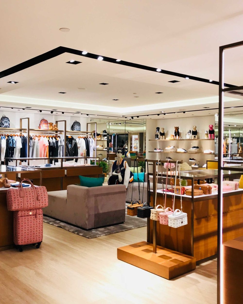 A quiet MCM retail floor with clothing racks and a single styled mannequin.