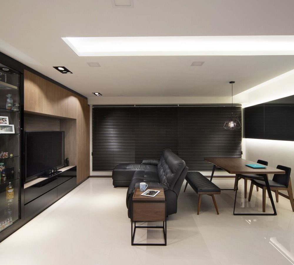 Wire cage pendant lights hang over a dining table with bench seating, set against dark venetian blinds and a glossy black feature wall.