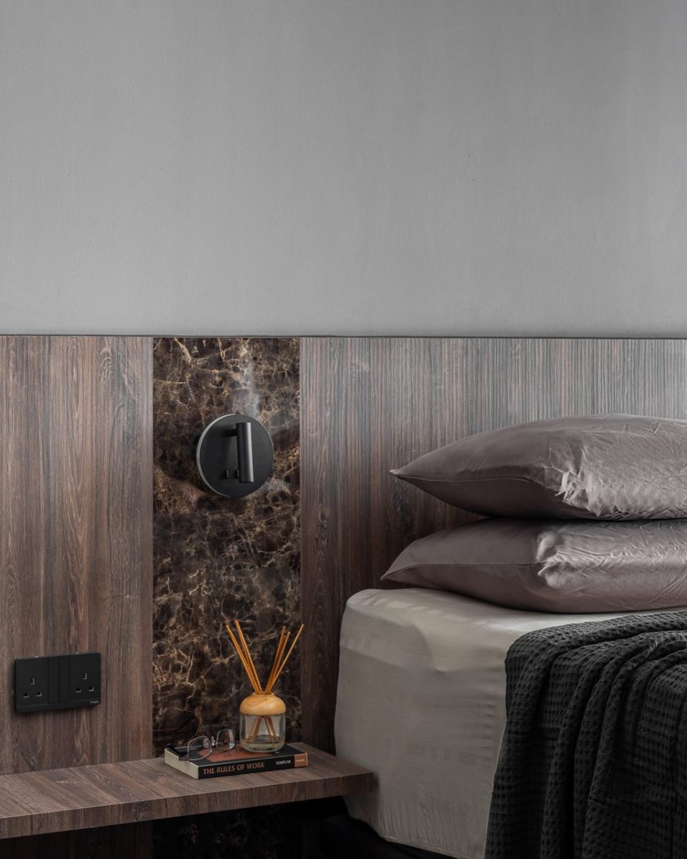 The bedside marble inset and its integrated switch plate catch the light beside neatly stacked pillows.