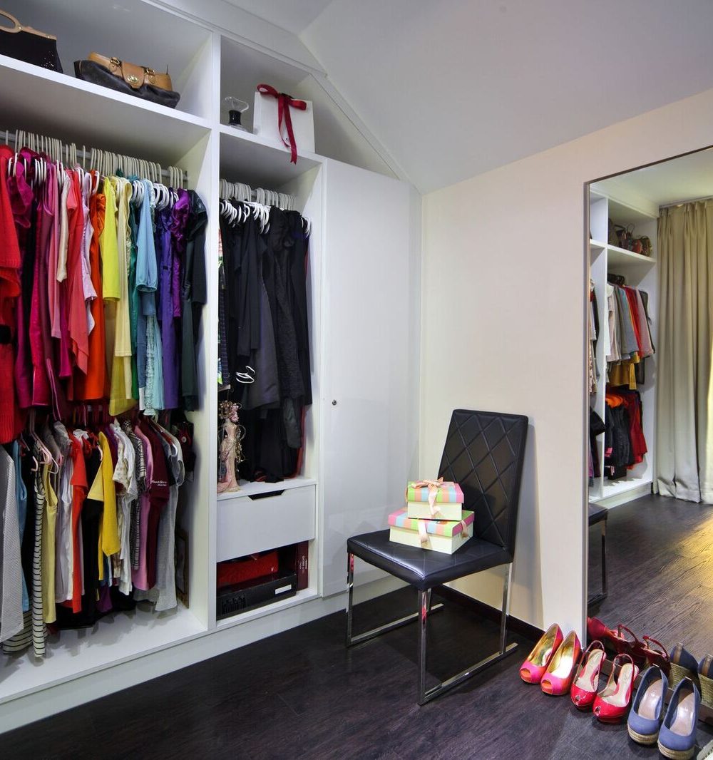 An open, colour-coded clothing rail keeps the wardrobe easy to navigate, mirrored on the opposite wall to maximise light.