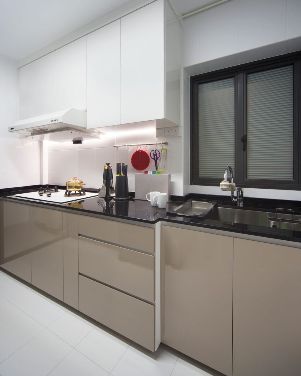 A two-burner gas hob and black stone counter make efficient use of a narrow galley layout, with open shelving for everyday utensils.