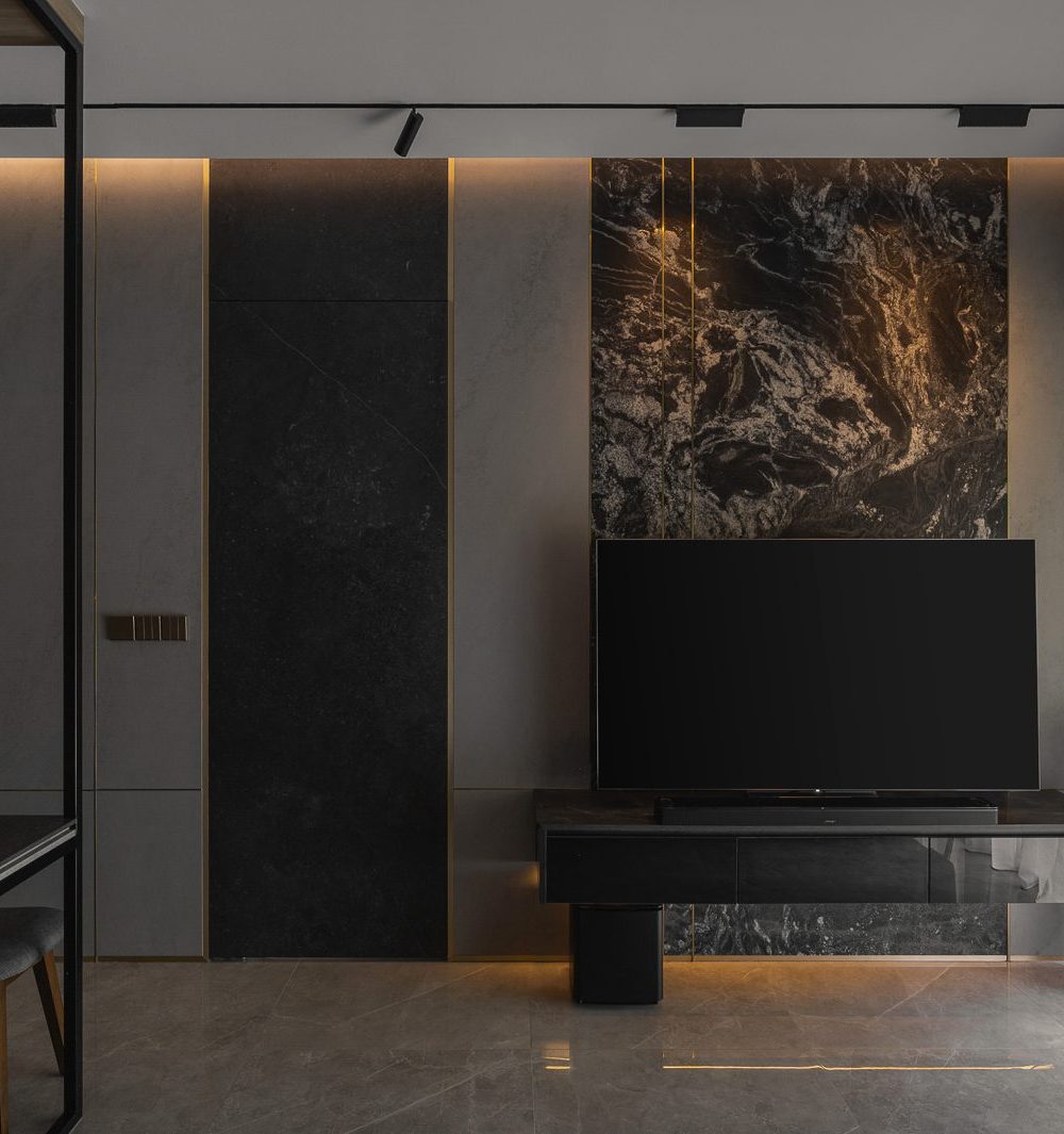 A black pivot door blends seamlessly into the marble-and-stone feature wall, hiding a second room behind it.