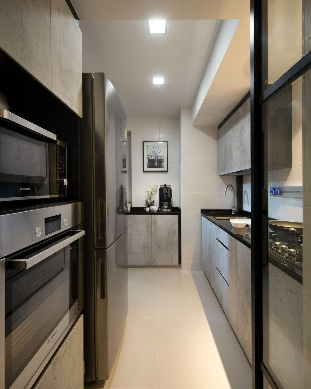 Concrete-textured cabinetry runs the length of the kitchen, fitted with a built-in oven and microwave stack and a black stone counter.