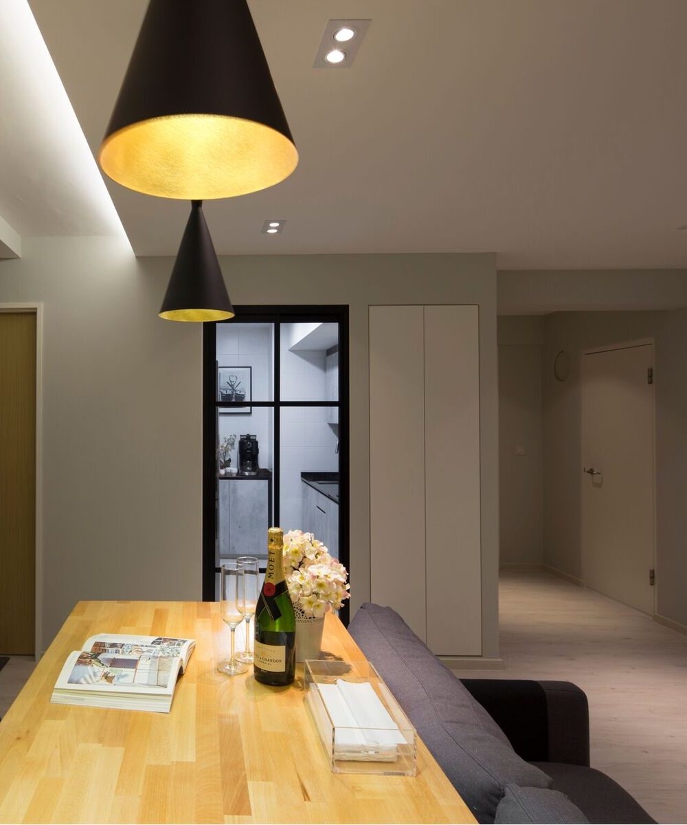 Two black-and-gold cone pendants hang low over the dining table, with a glimpse through to the kitchen's dark countertops beyond.