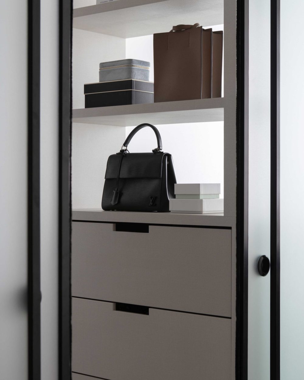 Structured bags and keepsake boxes are styled neatly on open shelving, making the wardrobe feel like a personal boutique.