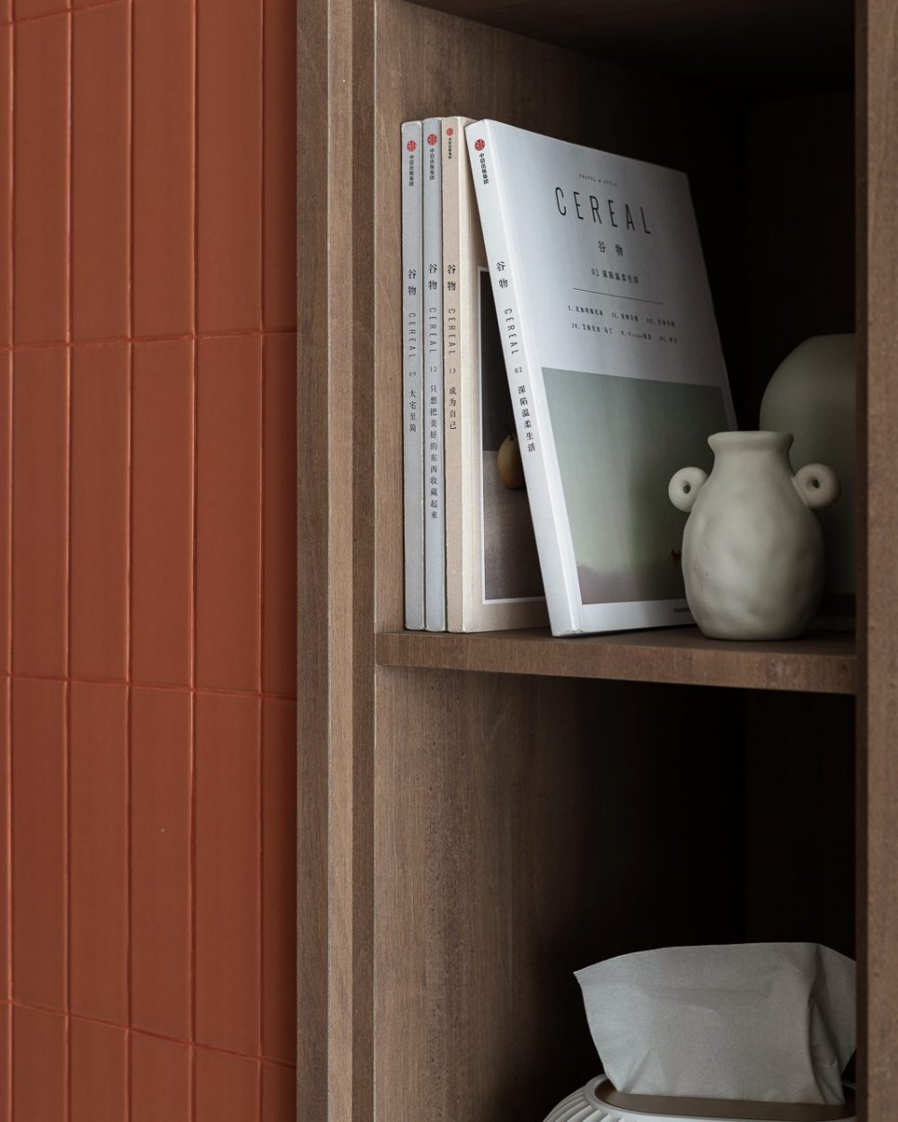 Design magazines and handmade ceramics are styled on open shelving, adding warmth and personality to the entrance wall.