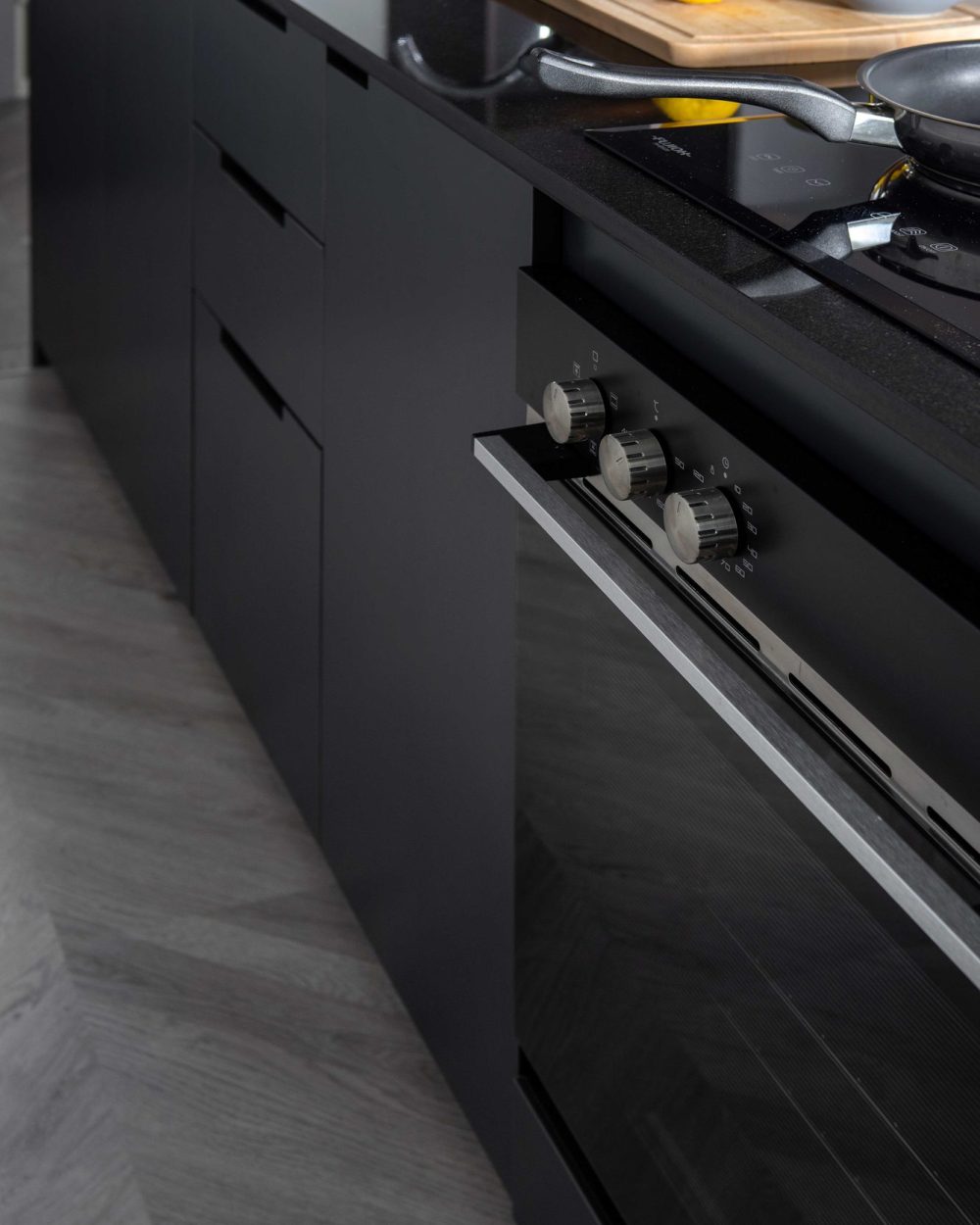 Fresh lemons and a chopping board sit ready on the black stone counter, beside a sleek built-in cooktop.