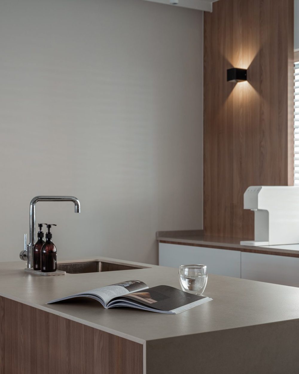 A knife block and stacked bowls sit ready at the hob, framed by a glass splashback and warm timber cabinetry.