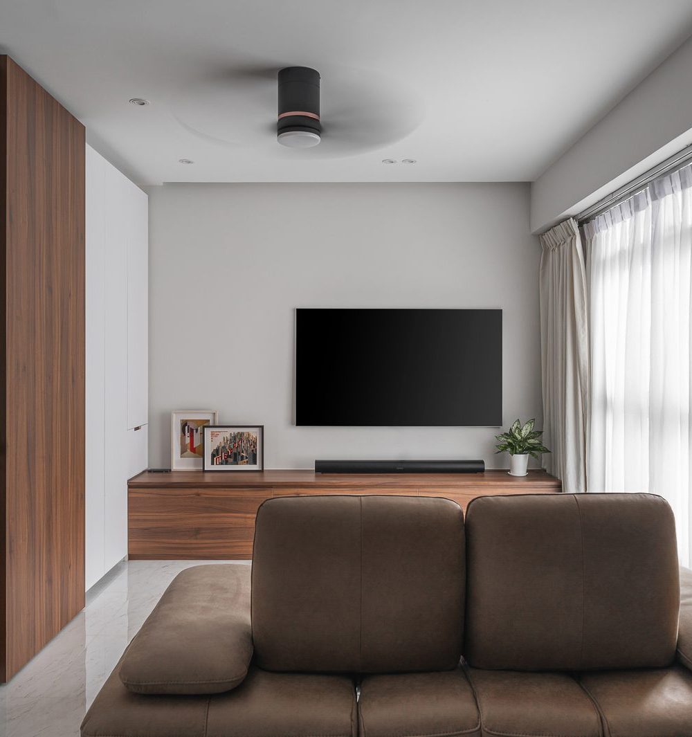 The same TV wall from a slightly wider angle, showing how the walnut cabinetry, white storage and glass display cabinet work together.