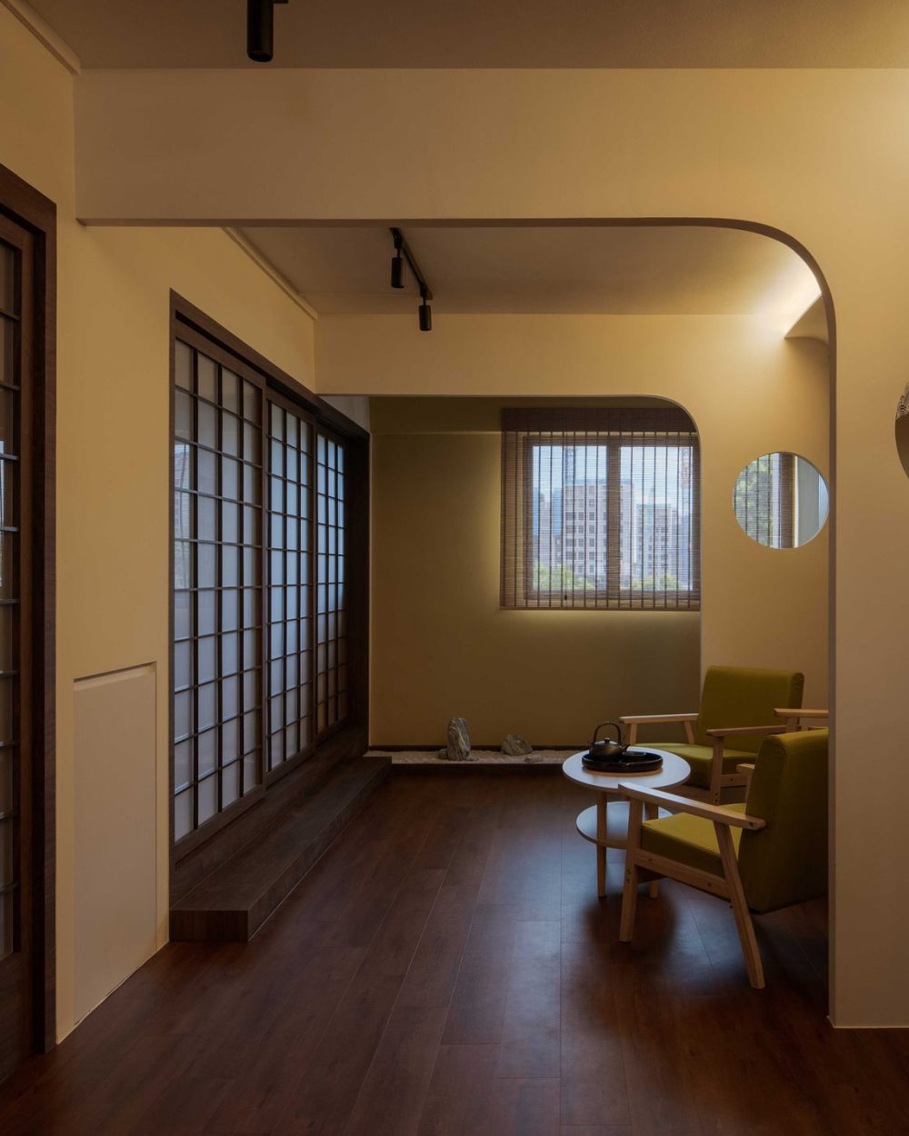 Sliding shoji doors line one side of the corridor, while circular cut-outs in the opposite wall frame views through to the sitting room.