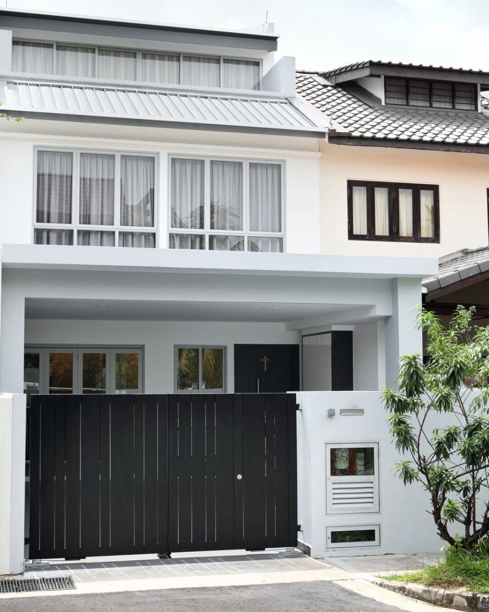 A two-storey white and grey facade with a slatted black gate gives this landed home a clean, contemporary street presence.