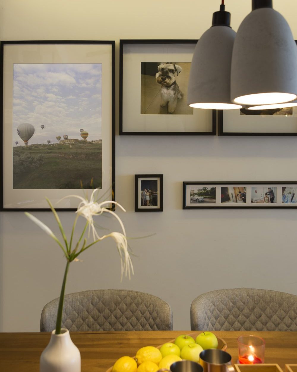 Framed travel photography and family portraits are arranged into a considered gallery wall beside the dining table.