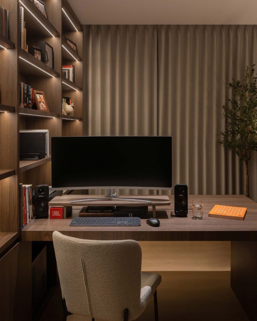 A second desk is fitted with a curved ultrawide monitor and bookshelving to match, giving the home office a setup built for long working sessions.