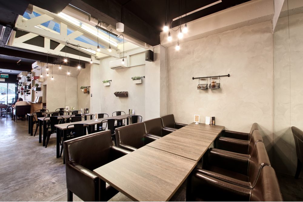 Deep leather banquette booths and timber tables offer a more intimate seating option, set against patterned floor tiles.