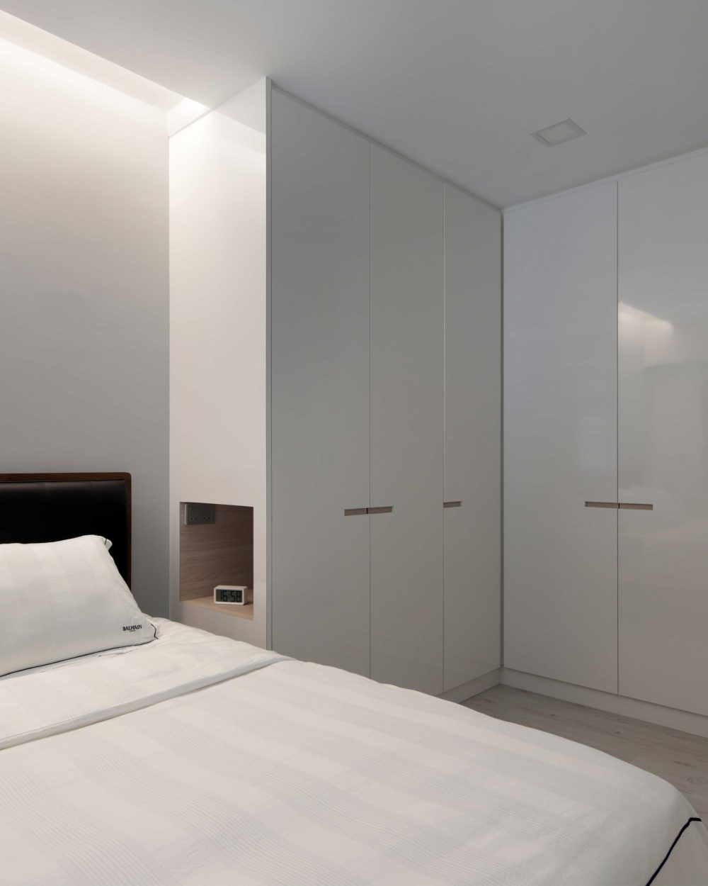 A button-tufted dark leather headboard anchors the master bedroom, with a built-in timber nightstand nook set into the wardrobe wall.
