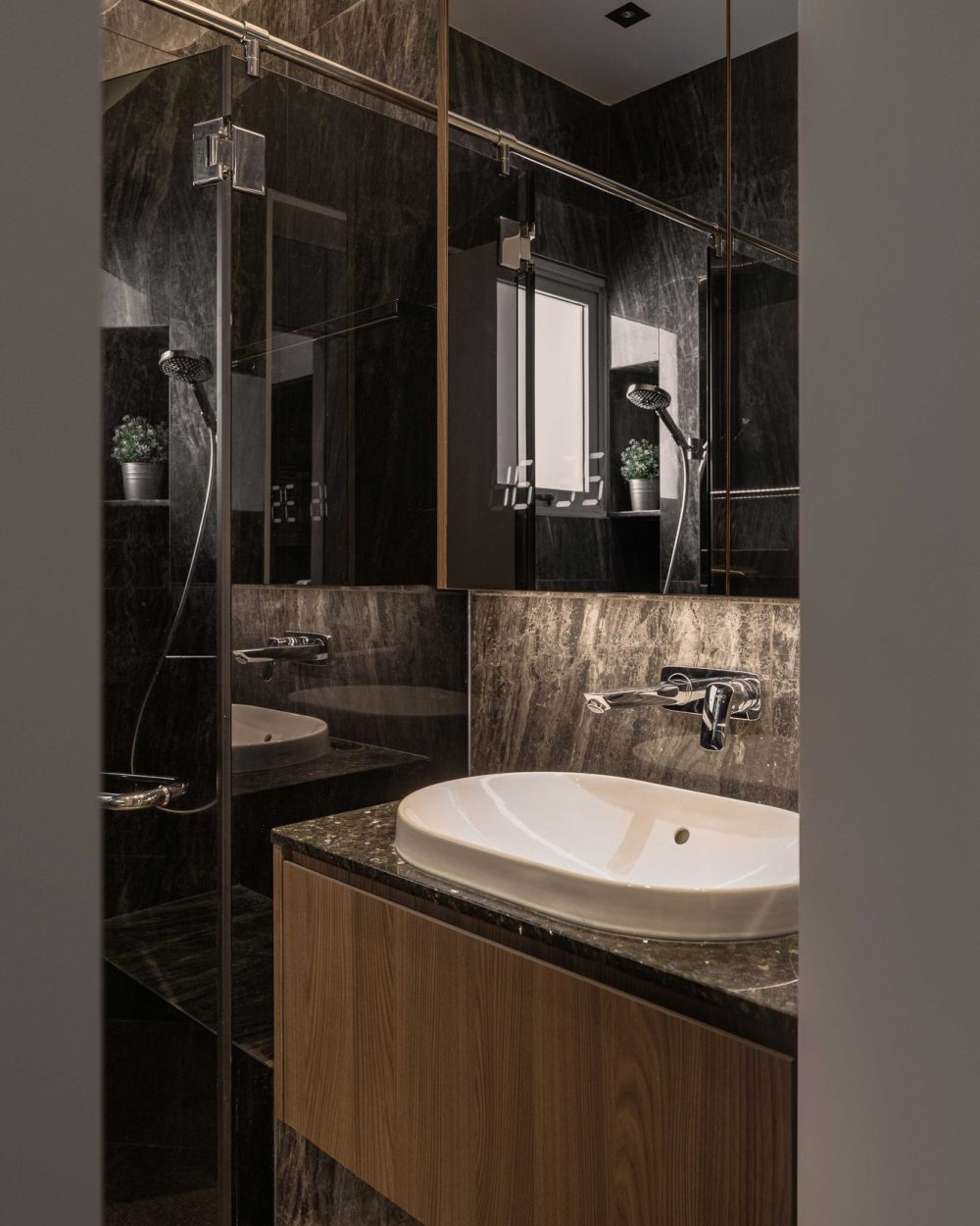 Charcoal stone tiling wraps the ensuite bathroom, paired with a timber vanity, wall-mounted tapware and a frameless glass shower.