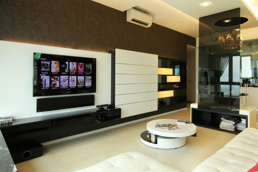 The living room continues the dark palette with a textured feature wall, a slatted white display panel and a wall-mounted television, set against warm