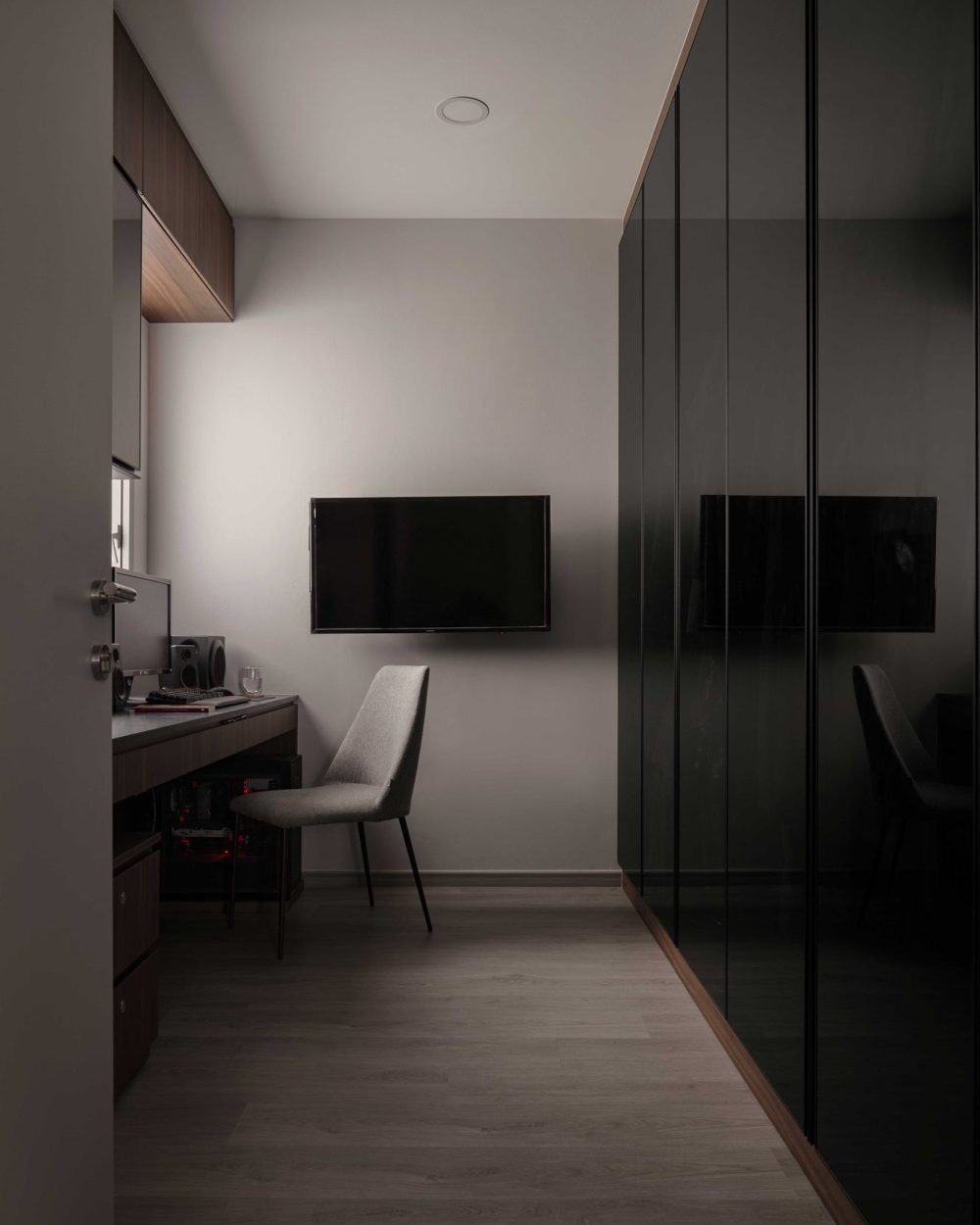 Glossy black wardrobe doors and a built-in desk give this study a moody, focused character, separate from the rest of the home's light palette.