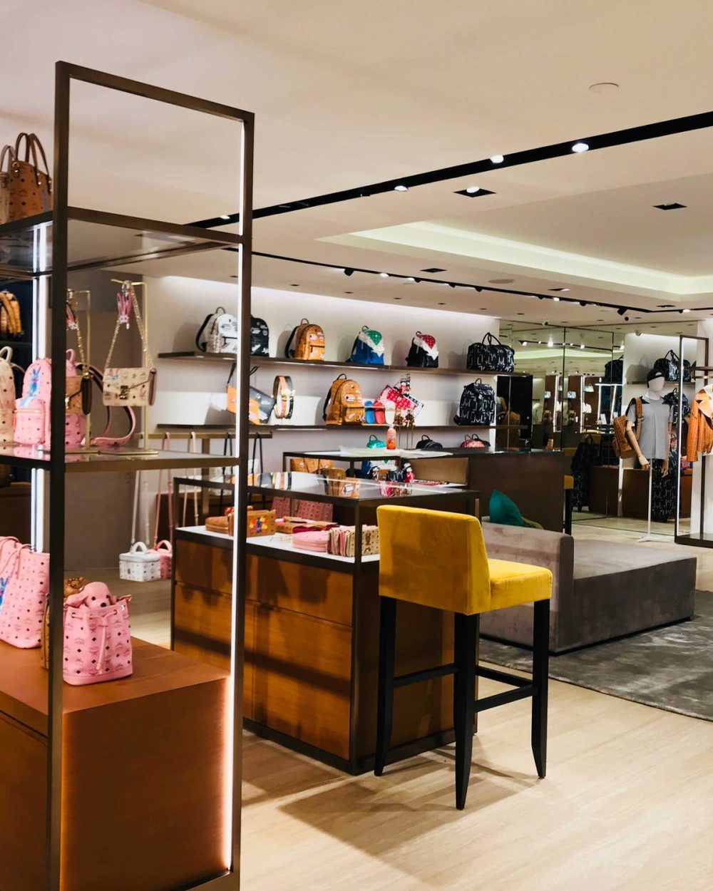 A deep view into the MCM store with backpacks, bag charms and clothing racks framed by mirrors.