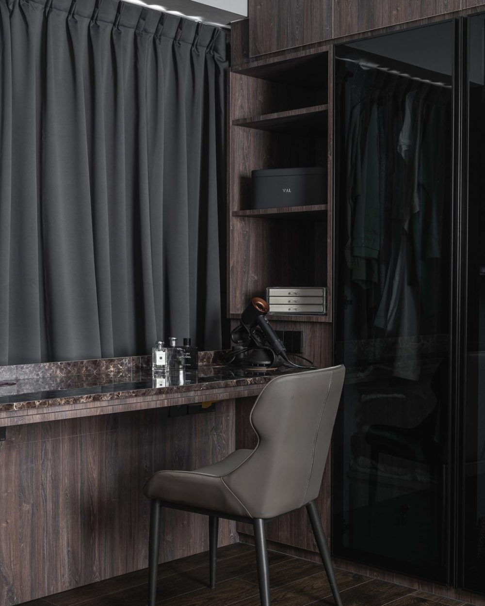 The marble counter continues beside the open wardrobe, styled simply with fragrance bottles and folded towels.