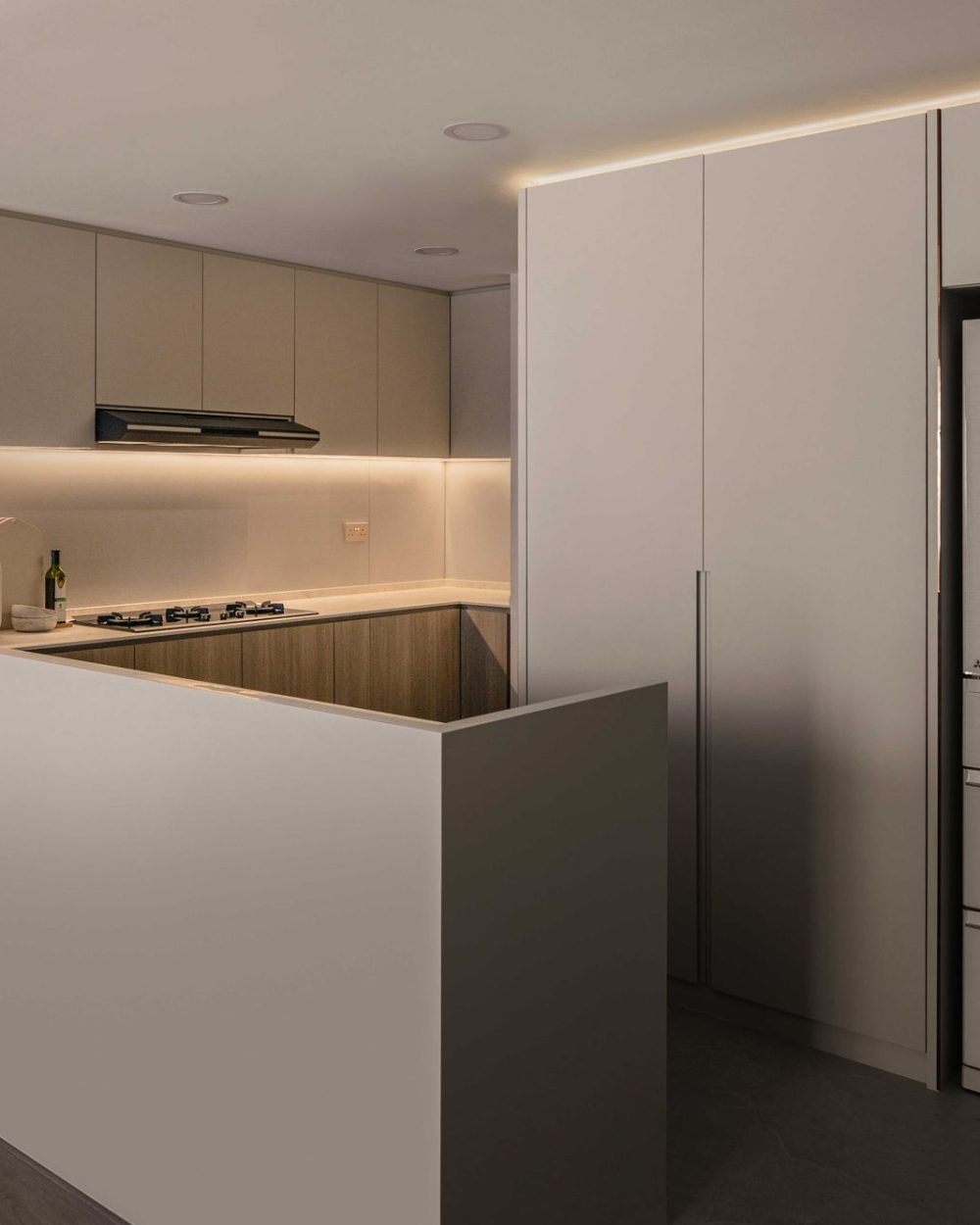 Timber lower cabinets and a glass splashback line the L-shaped kitchen, fitted with a gas hob and built-in extractor.