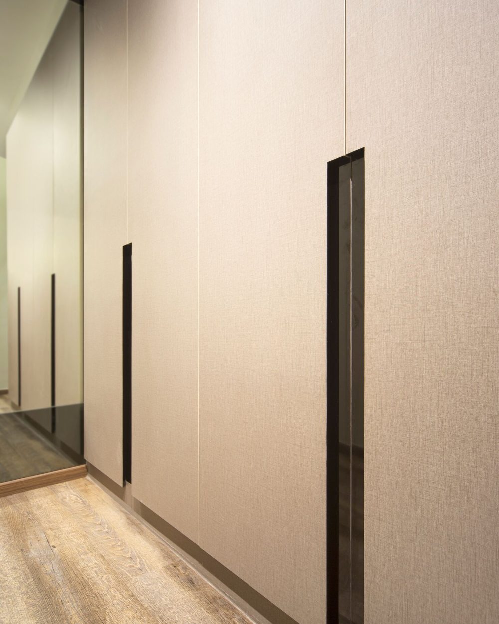A closer look at the wardrobe's linen-textured panels and slim recessed pulls, which run the full height of the storage wall.