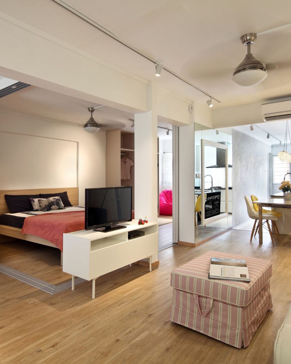 Full-height sliding doors let bedrooms open directly onto the living and dining area, keeping the small HDB flat feeling connected and flexible.