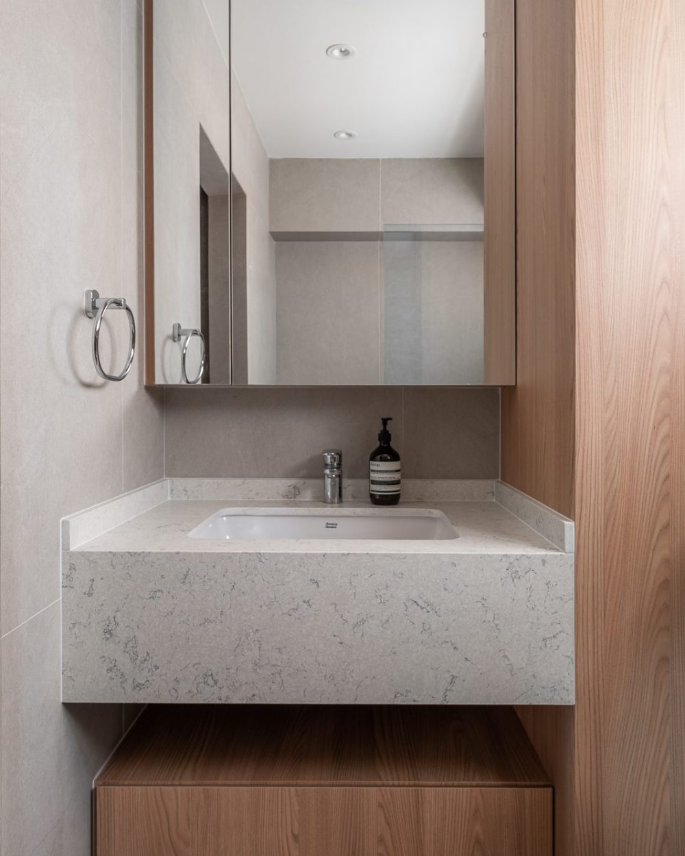A floating marble-topped vanity and mirrored cabinet keep this bathroom bright, framed by warm timber panelling.