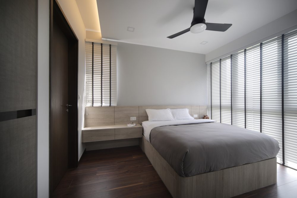 A long floating timber bench doubles as nightstands along the bedroom's window wall, framed by full-height venetian blinds.