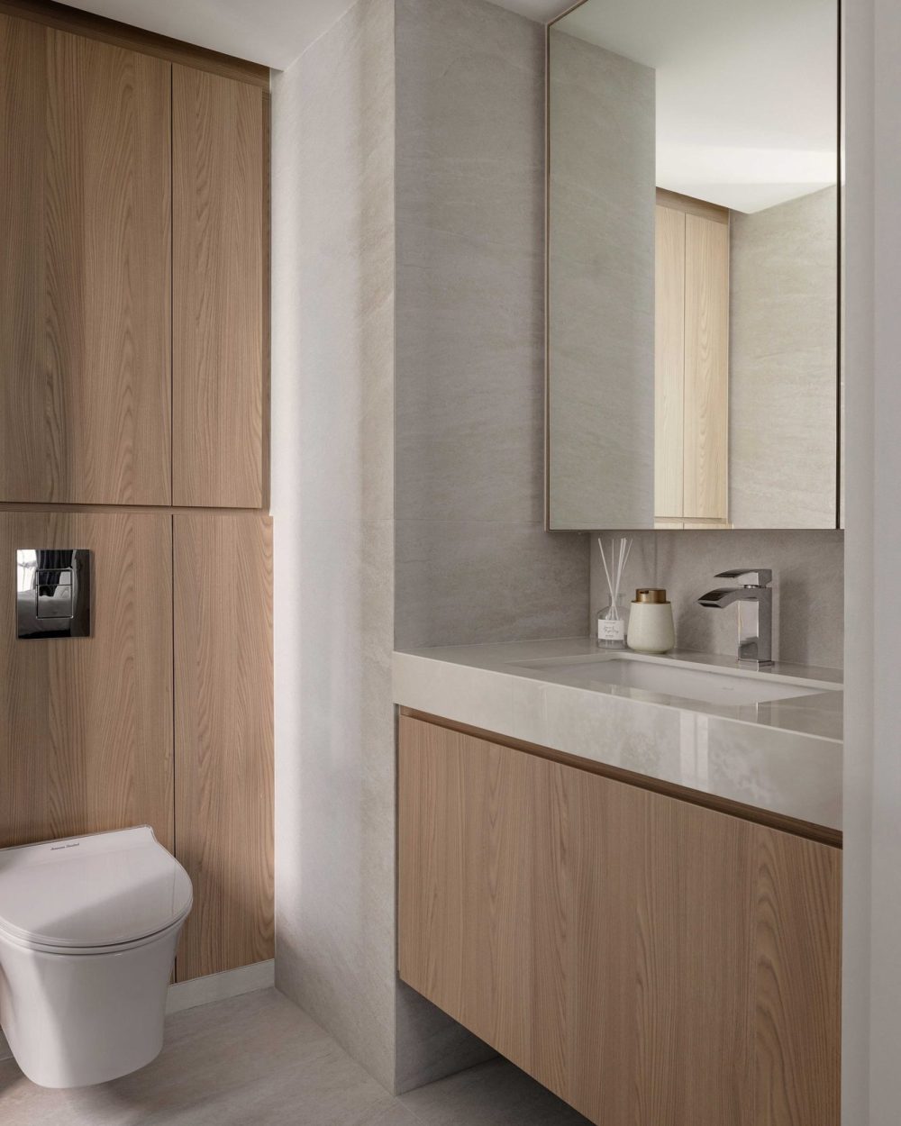 A closer look at the vanity's stone counter and timber cabinetry, lit by a warm cove light above the mirror.