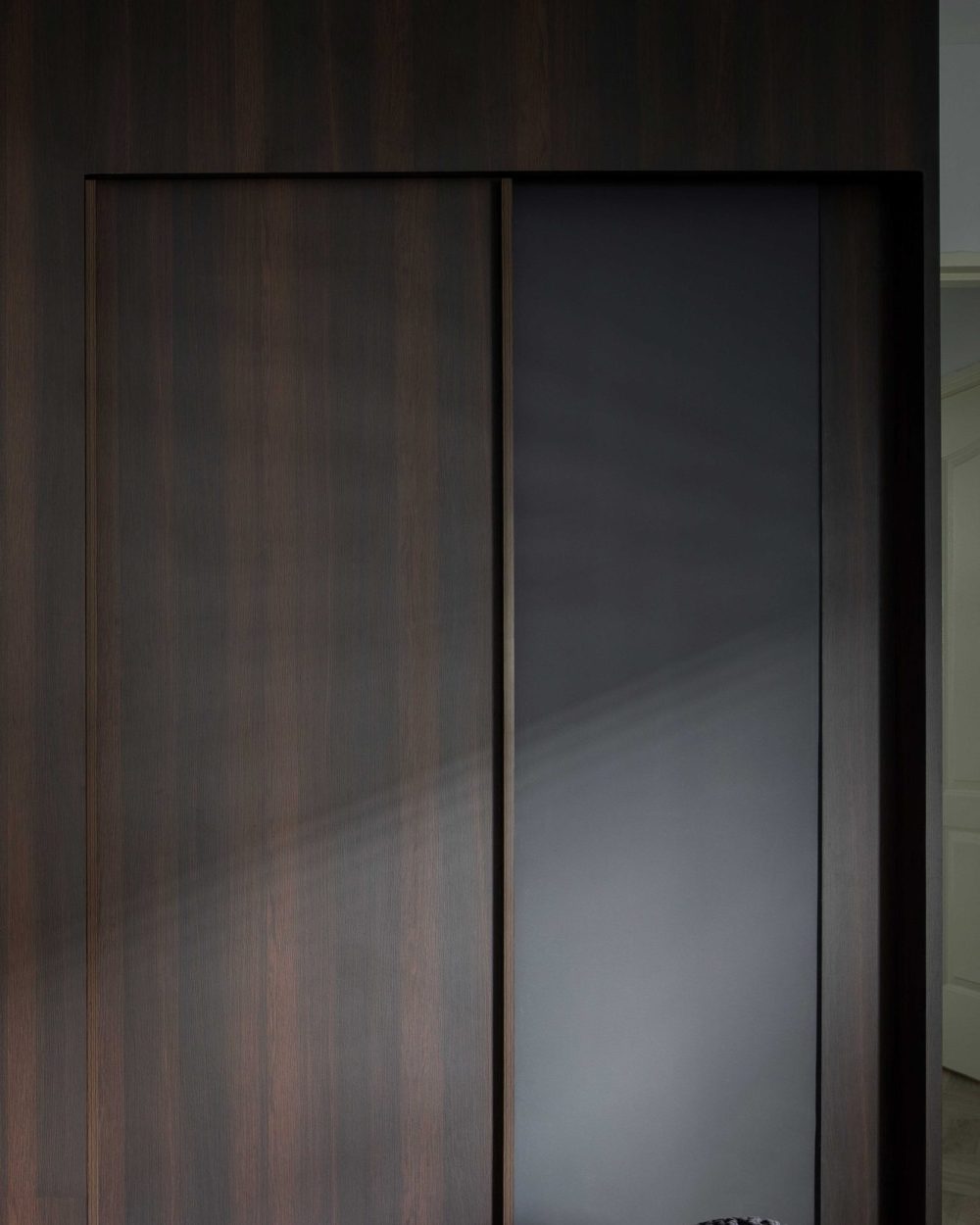 Dark timber wardrobe doors are paired with a frosted glass panel, adding texture without losing light.