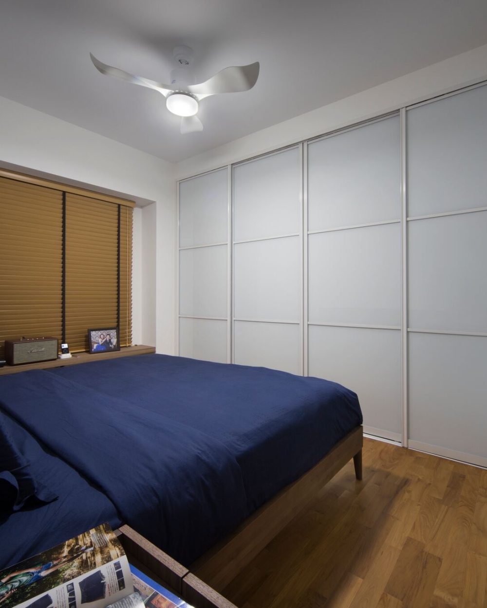 A closer look at the bedroom's frosted glass sliding wardrobes, which include an integrated shelf for a television and open storage.