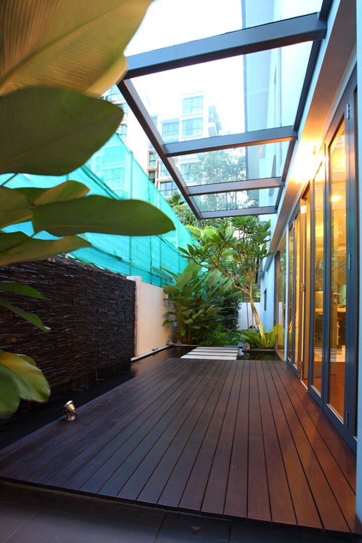 A glass-roofed deck runs alongside a stone-clad water feature, creating a sheltered outdoor space just off the living areas.