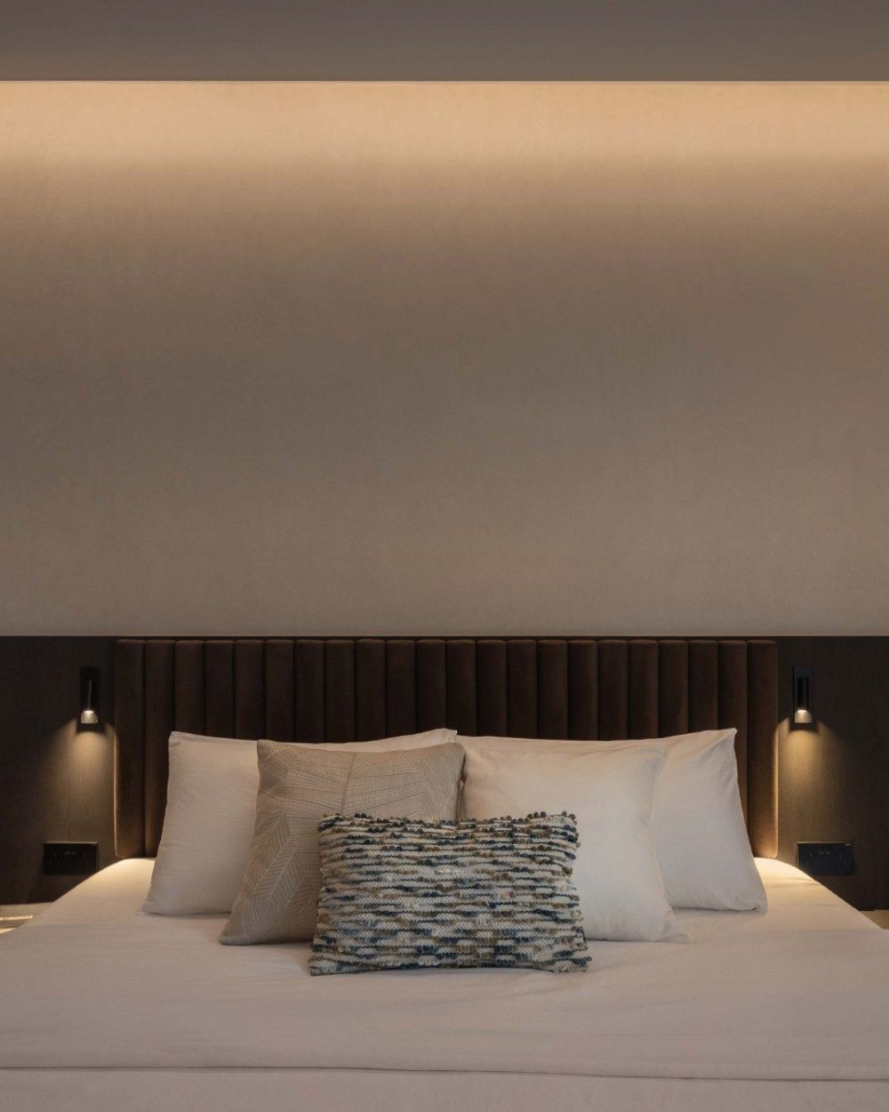 Layered pillows and a brass giraffe figurine on the nightstand give the bedroom a playful, personal touch against its otherwise tailored, tonal palett