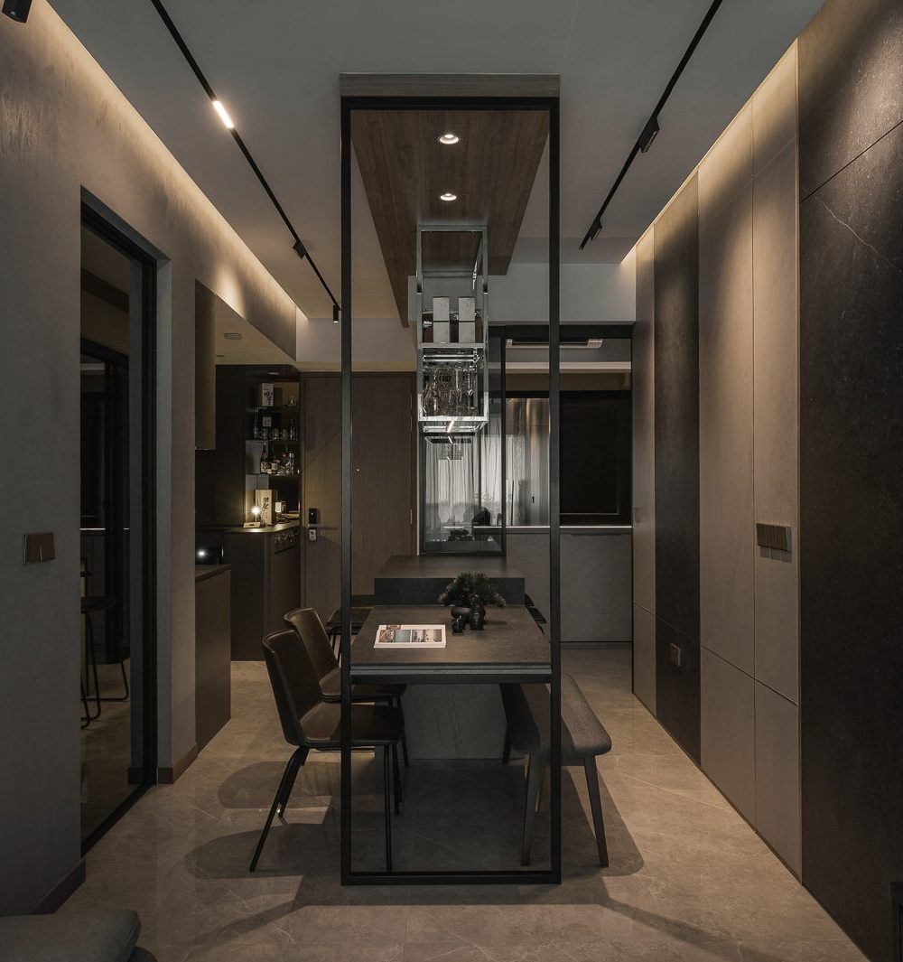 A suspended glass-and-steel wine rack anchors the dining area, framed by dark stone-clad walls and warm cove lighting.