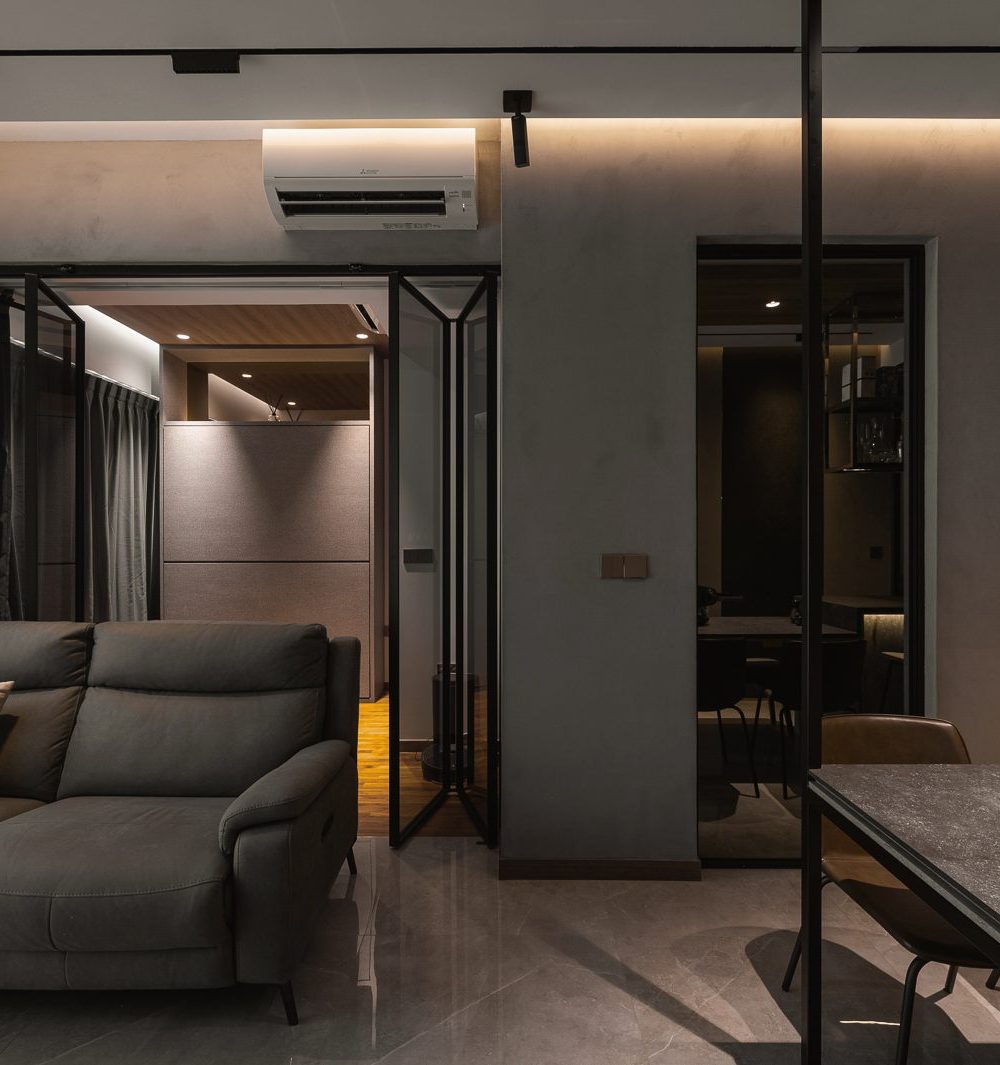 Sheer curtains and glass folding doors soften the transition between the living room and bedroom, framed by a leather sofa.