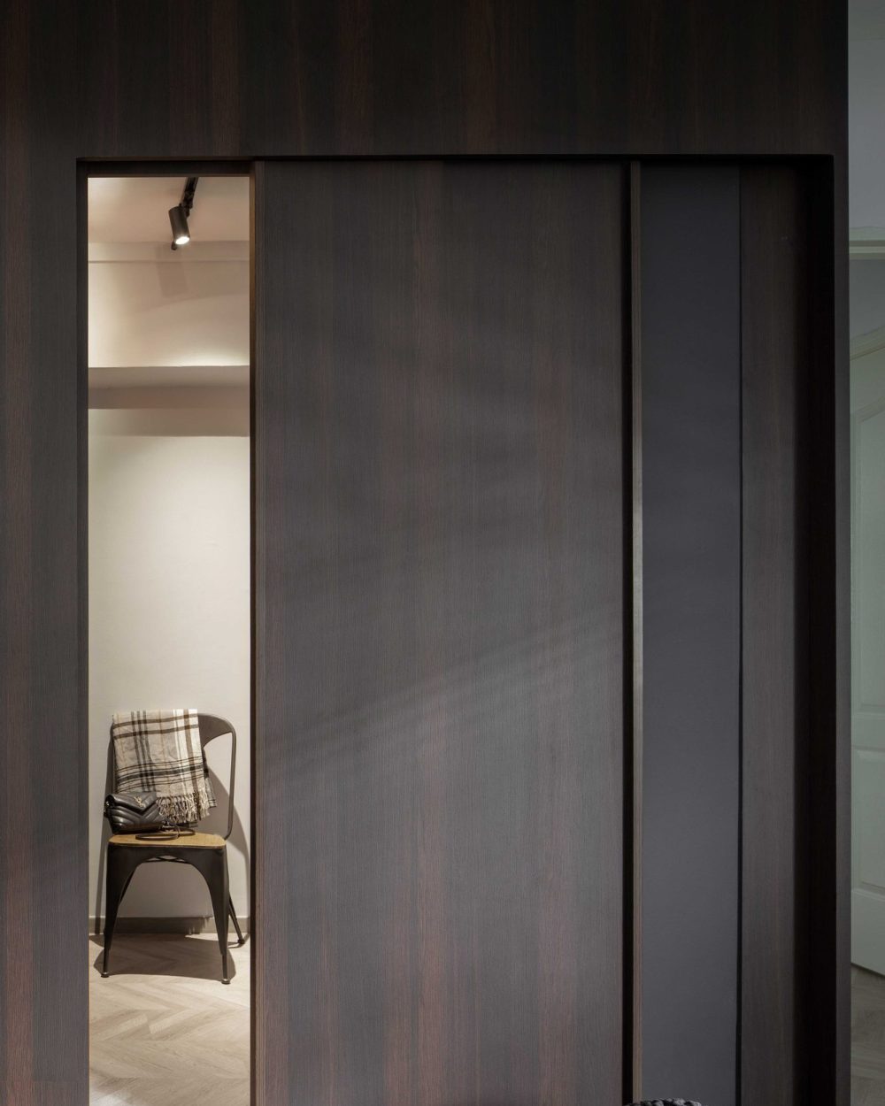 A sliver of open wardrobe door reveals a small dressing corner, styled with a tolix chair and a designer handbag.