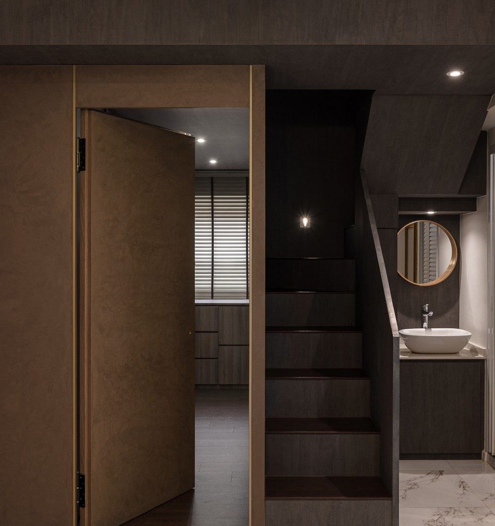 The same sliding door, opened, reveals a bedroom with timber wardrobes and window blinds just beyond the staircase and basin nook.