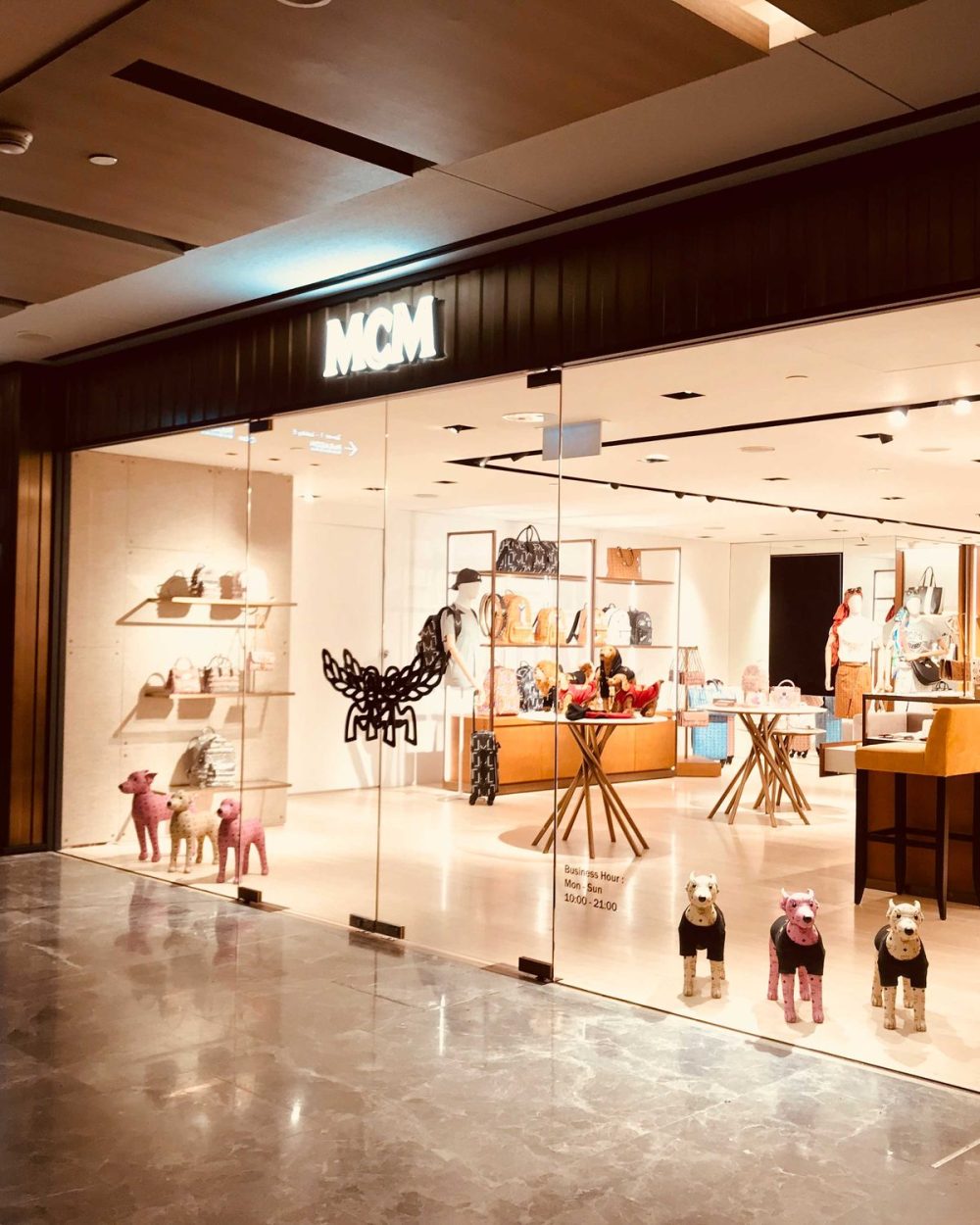 The MCM storefront at Paragon mall lit up after dark, with dressed canine figures in the window.