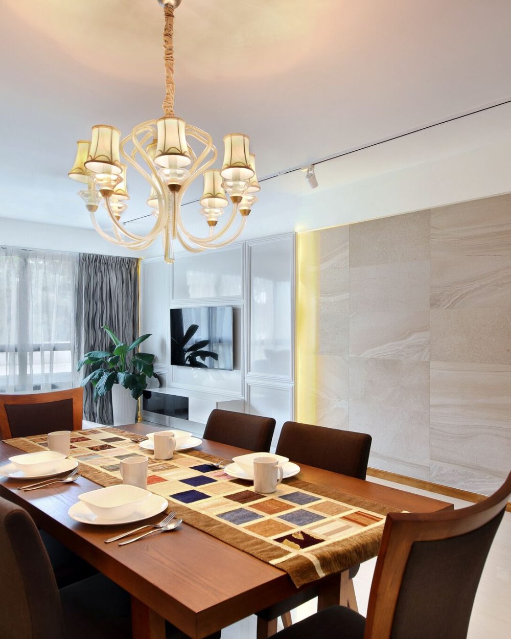 A crystal chandelier and stone-clad feature wall set a formal tone in the dining room, paired with a dark wood dining set for six.