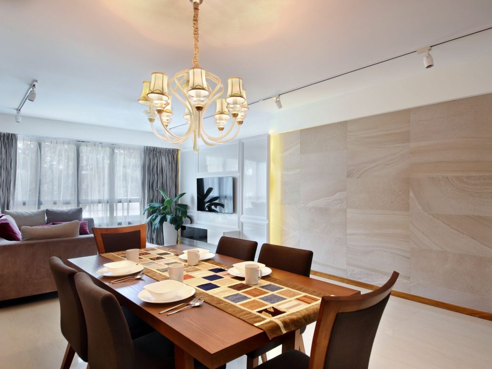 A crystal chandelier and stone-clad feature wall set a formal tone in the dining room, paired with a dark wood dining set for six.