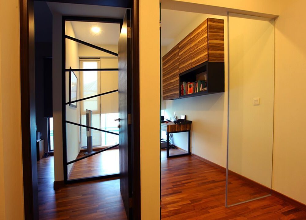 A black-framed grid pattern glass door adds a graphic touch to the hallway, opening onto a timber-panelled study beyond.