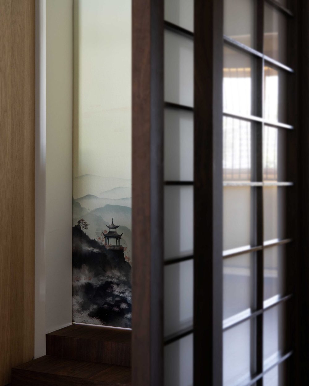 A mural of mist-covered peaks, a hilltop pavilion and a flock of birds is hand-painted directly onto a sliding door panel.